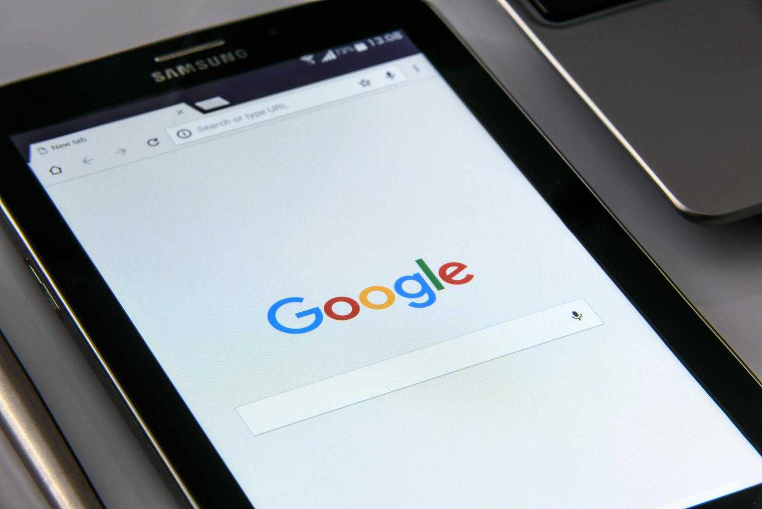 Tablet Samsung z otwartą stroną główną Google na białym tle interfejsu.