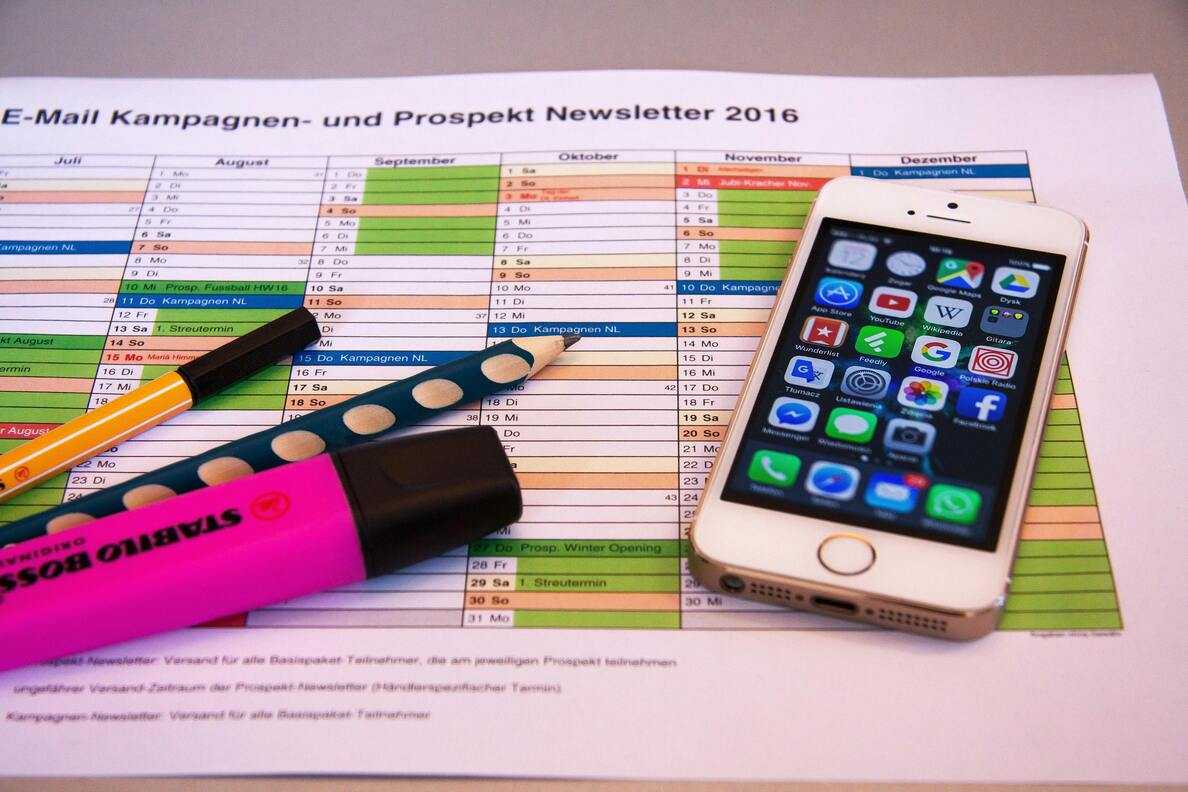  Smartfon iPhone leży na papierze z kalendarzem lub planem kampanii marketingowej.