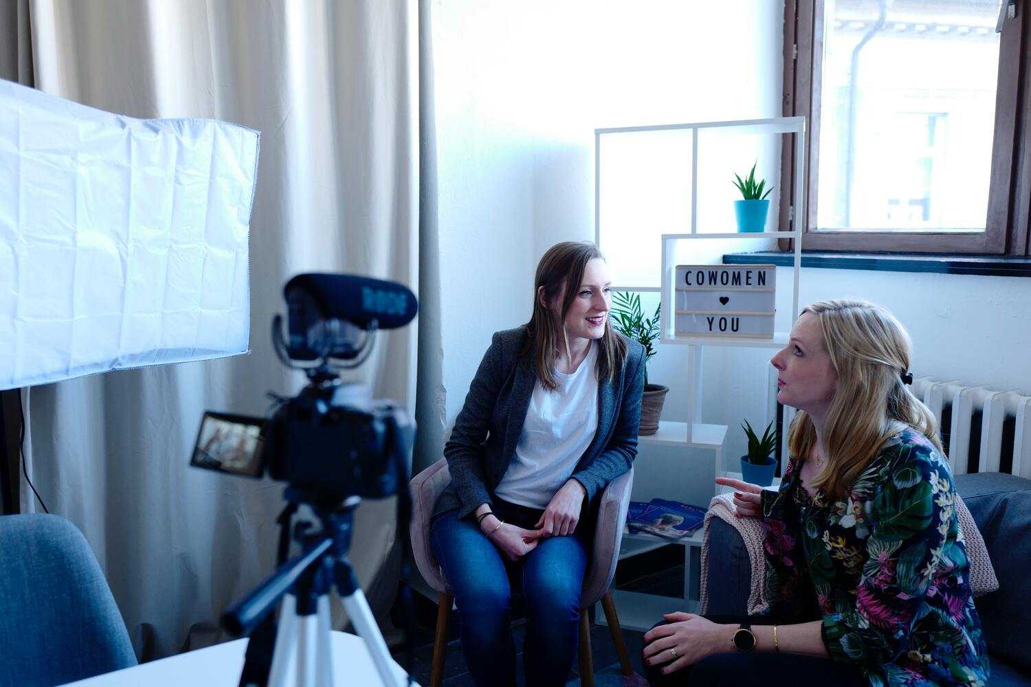 Dwie kobiety rozmawiające podczas nagrania wideo w domowym studio z kamerą i oświetleniem